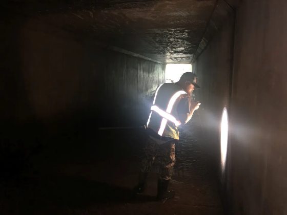 inspector in tunnel shining flashlight