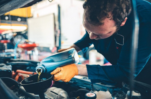 mechanic pouring oil into car